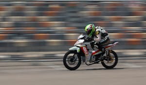 Dynamic shot of a motorcycle racing at high speed on a race track outdoors.