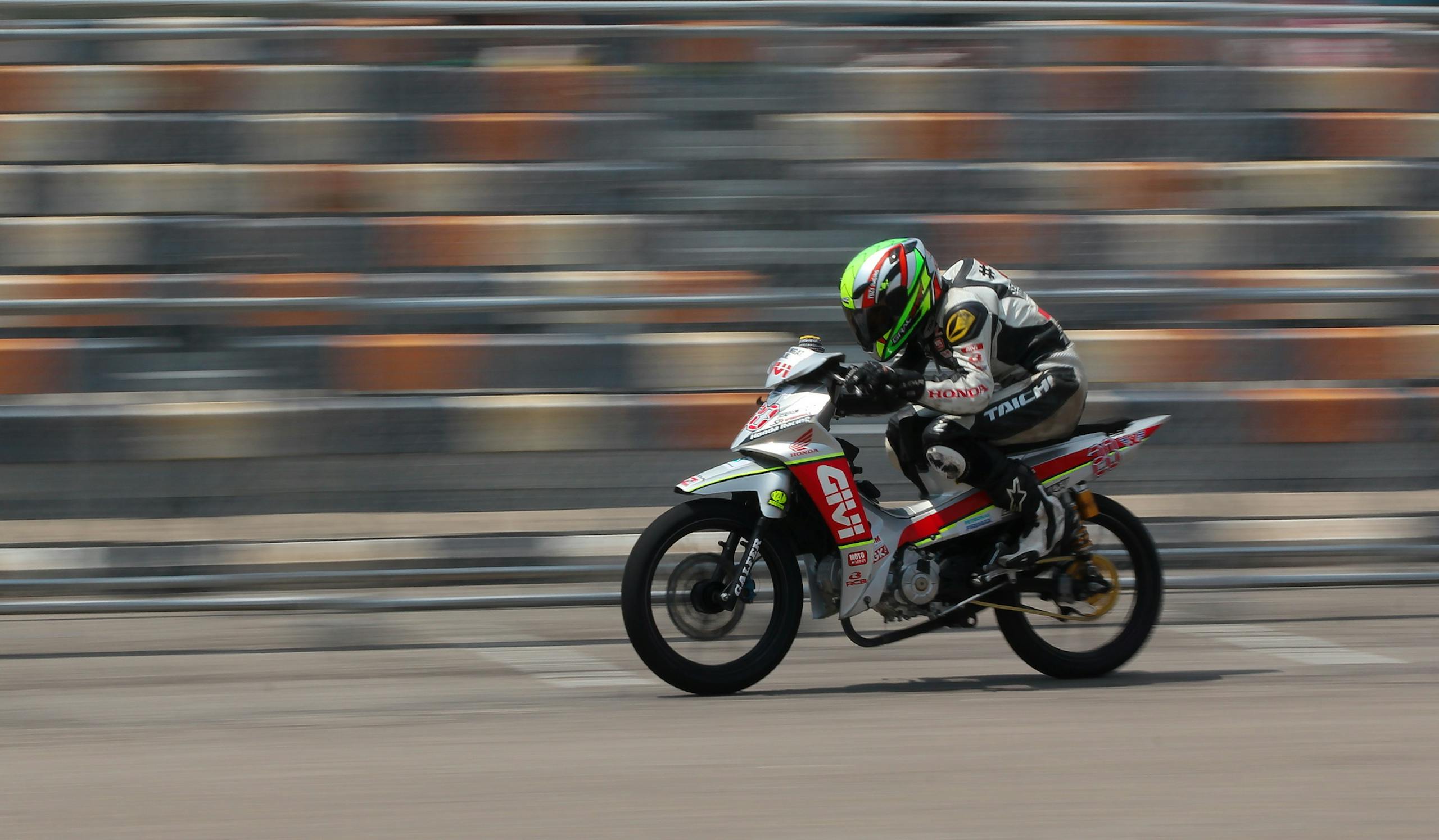 Dynamic shot of a motorcycle racing at high speed on a race track outdoors.